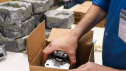 A production worker for RIS packs individual products for distribution.