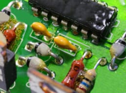 Close up of many components on an electronic circuit with the resistors coated with resin to protect them